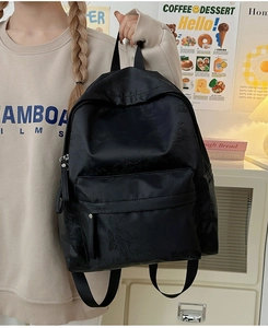Detail of minimalist black backpack featuring subtle leaf texture and Hoog brand logo