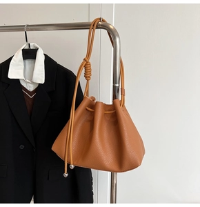 Detail of caramel pleated bucket bag with litchi grain leather and silver ball charms
