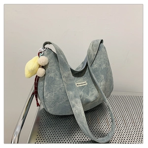 Detail of light blue hobo bag with corduroy texture and cute yellow duck charm