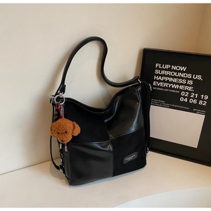 Detail of black patchwork tote bag with suede textures and a cute teddy bear charm