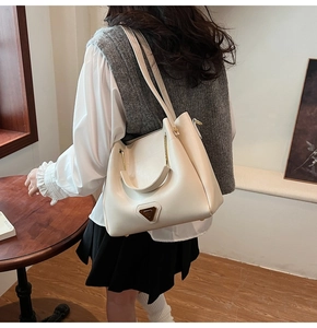 Détail du sac seau crème montrant les garnitures métalliques et les coutures propres