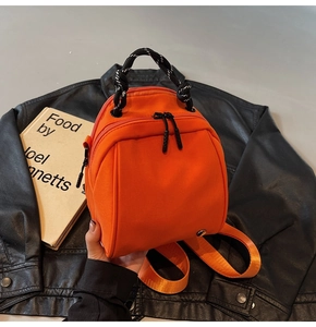 Macro detail van levendige oranje nylon mini-rugzak met geweven handvat op een jas