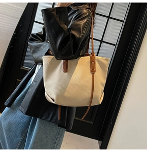 Close-up of beige twill texture tote bag with slim dark brown leather shoulder straps