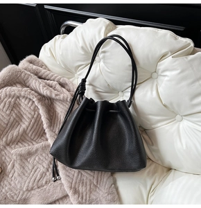 Detailed view of black pebbled leather texture and elegant drawstring closure on bucket bag