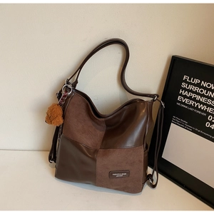 Detail of the brown patchwork tote bag with a plush bear charm on white surface