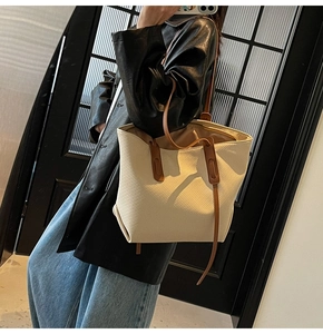 Detail of the cream-white tote bag with twill texture and brown leather shoulder straps