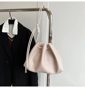 Detail of off-white lychee leather bucket bag featuring drawstring and knotted rope strap