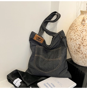 Detail shot of navy denim tote bag with yellow contrast stitching and leather crown patch