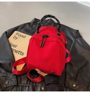 Detail van de rode nylon rugzak op leren jack met geweven touwhandvat en dubbele ritssluiting