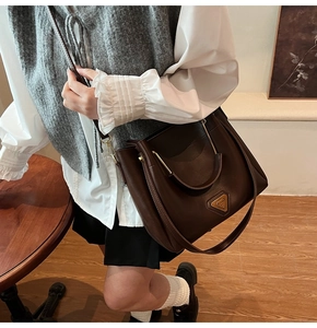 Détail du sac seau marron foncé avec ornement triangle doré et texture du matériau