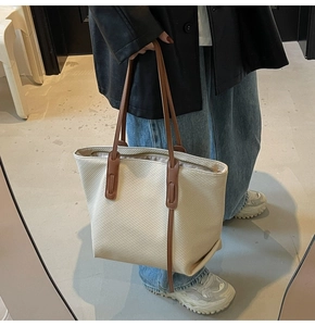 Detail of minimalist cream tote bag showing fine twill texture and brown leather straps