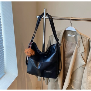 Detailed view of black PU leather hobo bag featuring a cute brown teddy bear keychain charm