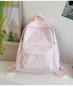 Detail view of pink nylon backpack featuring Hoeg embroidery and front zipper pocket