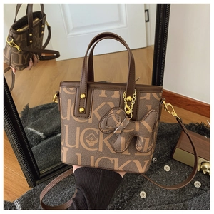Detailansicht der braunen Leder-Eimertasche mit Lucky-Print und Hunde-Anhänger
