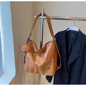 Close-up of caramel patchwork leather tote bag featuring a cute teddy bear charm