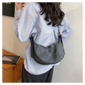 Detail of dark grey crescent bag with leather trim and gold metal adjustment buckle