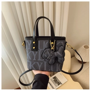 Detail der grauen Monogramm-Tasche mit Goldnieten und süßem Welpen-Anhänger
