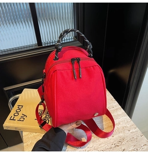 Detail of red canvas shell bag showing woven handle and smooth double metal zippers