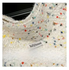 Nahaufnahme von weißem Strickstoff mit bunten Punkten und Jollyhouse-Markenetikett