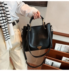 Vue détaillée du sac seau en cuir noir mat avec boucle métallique triangulaire dorée
