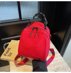 Detail of red nylon mini bag with woven rope handle and dual zipper closure