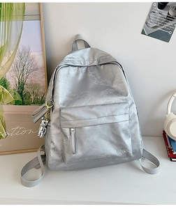 Detail of silver-grey backpack with jacquard texture and metallic bear pendant charm