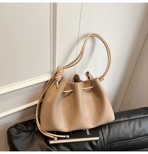 Detail of beige pleated bucket bag featuring lychee grain leather and metallic drawstring beads