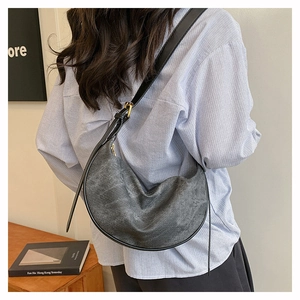 Detail of dark grey crescent shoulder bag with adjustable strap on a minimalist model