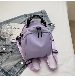 Detailweergave van een lila mini nylon rugzak met ritsen en verstelbare paarse riemen