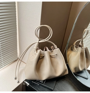 Detail of minimalist oatmeal drawstring bucket bag with litchi texture and metal beads