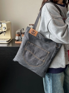 Large denim tote bag in dark grey with yellow stitching and leather crown logo patch