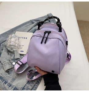 Detail van paarse nylon mini rugzak met dik geweven handvat en dubbele ritssluitingen