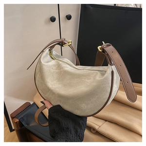 Detail of crescent crossbody bag with beige suede texture and dark brown leather trim
