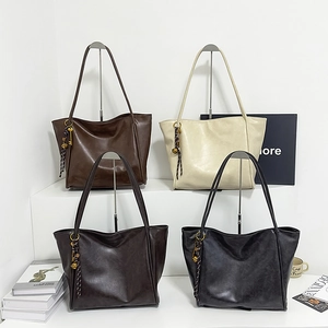 Detalle de cuatro bolsos tote de cuero sintético en marrón oscuro, crema, gris y negro