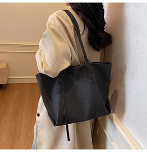 Detail of a large dark gray tote bag showing twill fabric texture and sleek shoulder straps