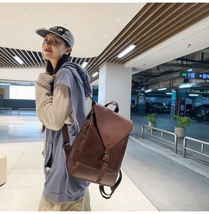 Seitenansicht des Retro-Rucksacks aus braunem Leder an einem Modell in urbaner Umgebung