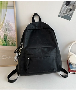 Close-up of black floral jacquard backpack with a stylish silver mechanical bear charm