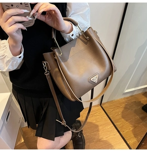 Détail du sac seau taupe avec poignée métallique ronde et plaque logo triangulaire