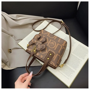 Detail der braunen Bucket Bag mit Lucky-Print und süßem Hasenanhänger auf einem Buch