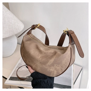 Detail showing retro brown crescent bag with leather trim and gold metal hardware