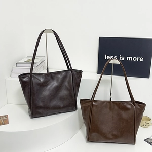 Detalle de bolsos tote grandes de cuero sintético en marrón oscuro y medio con textura fina