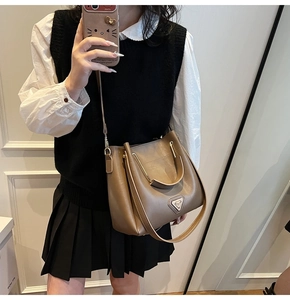 Détail du sac seau en cuir marron avec poignée ronde dorée et plaque logo métallique