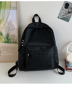 Detail of black nylon backpack with subtle texture and front zipper pocket