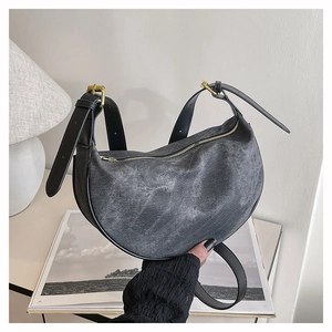 Detail of black crescent crossbody bag with washed canvas texture and golden hardware
