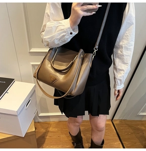 Détail du sac seau en cuir marron foncé montrant le grain de litchi et les garnitures