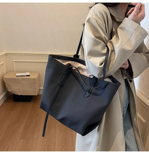 Detailed view of black woven tote bag showing large capacity and slim leather straps