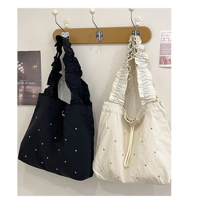 Detailansicht großer Tragetaschen in Schwarz und Beige mit Metallnieten und Raffträgern