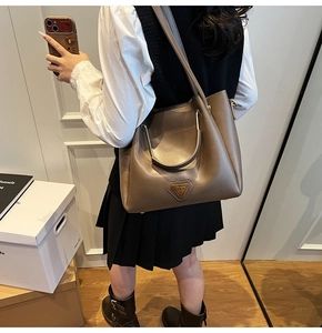 Sac fourre-tout en cuir marron avec poignée dorée semi-circulaire et logo en métal