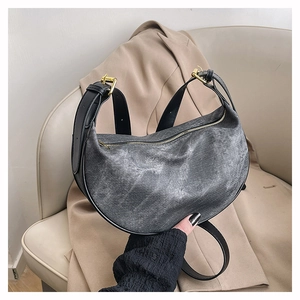 Close-up of crescent bag with washed fabric texture and black leather strap details