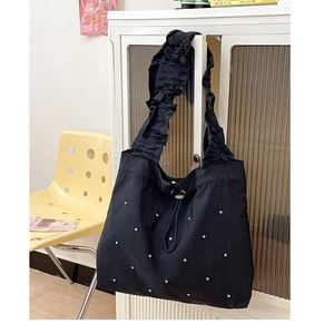 Detail der schwarzen Shopper Tasche mit silbernen Nieten und gerafftem Schultergurt
